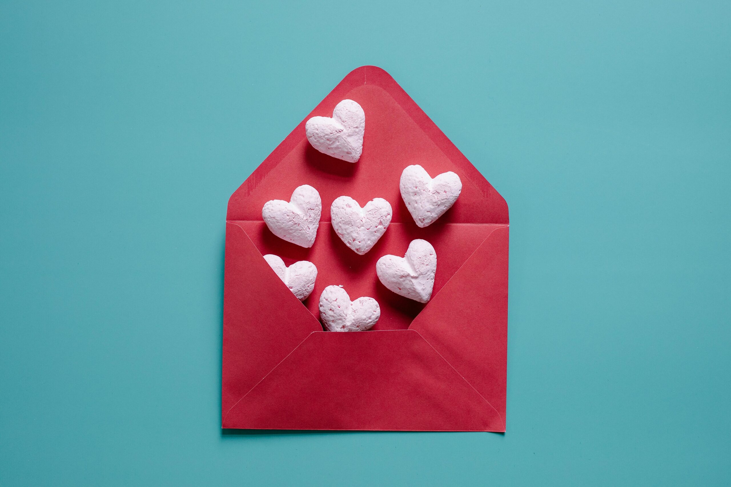 A vibrant red envelope with heart-shaped objects on a contrasting blue background for Valentine's Day.