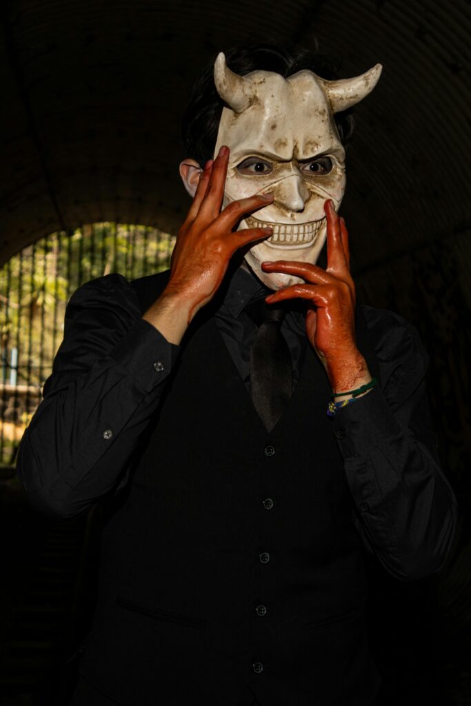A mysterious man in a white devil mask poses elegantly in a dark tunnel in Ciudad de México, CDMX, México.