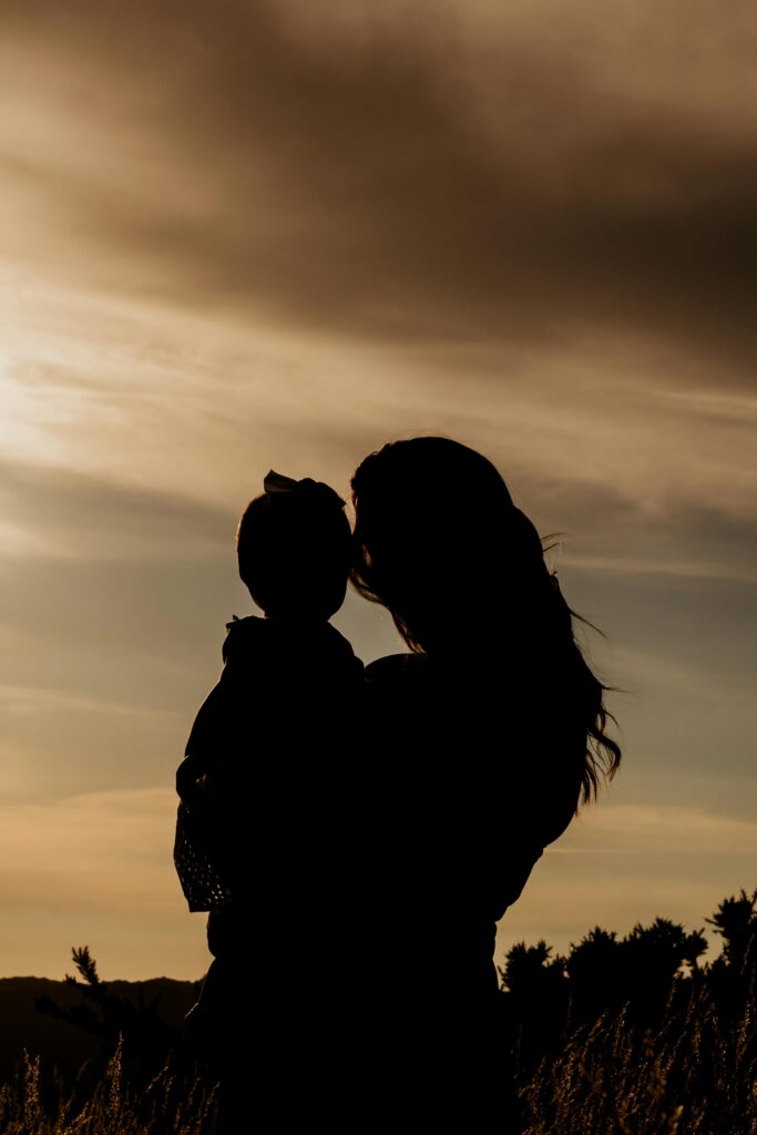 A touching silhouette of a mother holding her child during a scenic sunset.