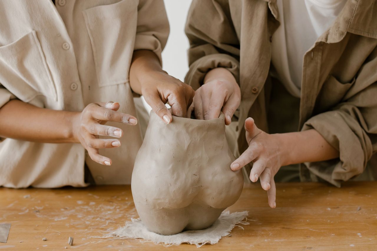 Close-up of hands shaping clay in a pottery workshop, showcasing the art of crafting.
